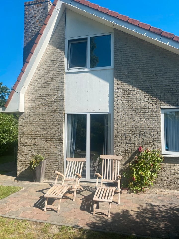 Giebelseite mit zwei Holzliegen und Blumen