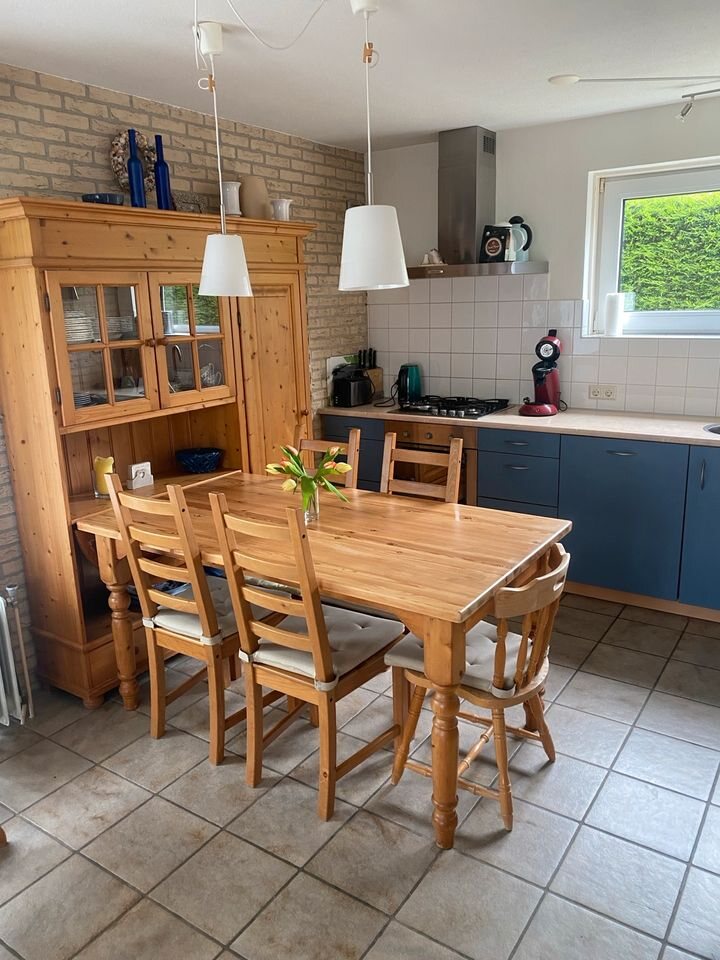 Esstisch aus Holz und Küche mit blauen Fronten