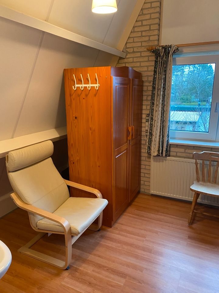 Sessel und Holzschrank im Dachzimmer